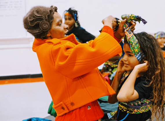 Image of a teaching artist wrapping a child's head band